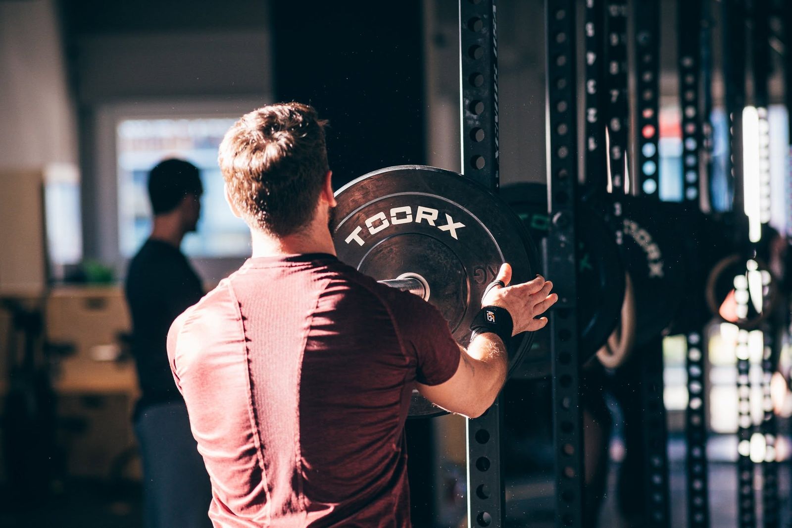 Un atleta carica un disco sul rack in sala pesi