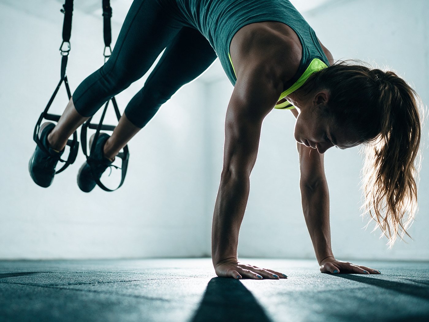 Un’atleta in plank con i piedi nelle cinghie TRX